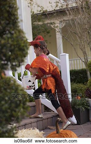 Stock Image - Girl with Jack O' Lantern bucket ascending steps. Fotosearch