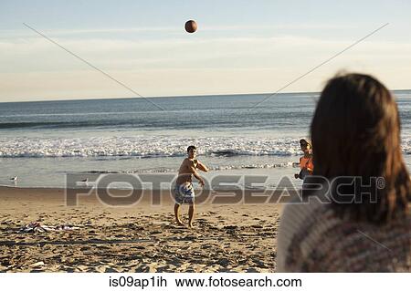 Stock Image - Group of friends playing on beach with ball. Fotosearch