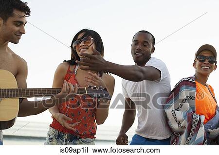 Group of friends singing and playing guitar on beach View Large Photo Image Stock Image - Group of friends singing and playing guitar on beach. Fotosearch