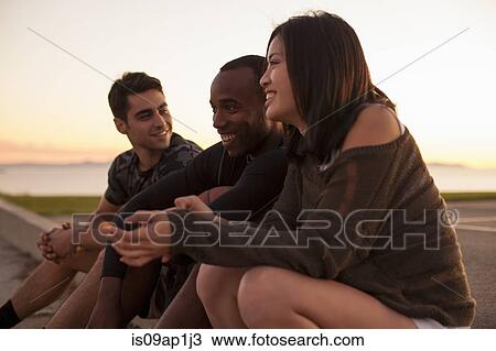 "Group of friends sitting on edge of sports court, outdoors" View Large Photo Image Stock Image - "Group of friends sitting on edge of sports court, outdoors". Fotosearch