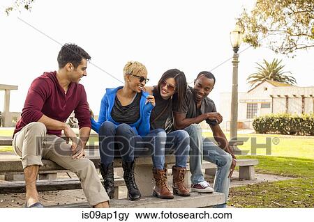 Group of friends sitting together on bench View Large Photo Image Stock Photo - Group of friends sitting together on bench. Fotosearch