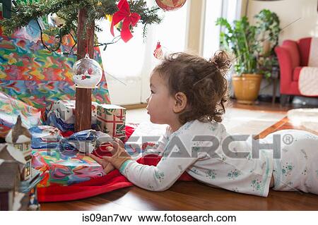 Little girl admiring Christmas ornaments on tree View Large Photo Image Stock Photo - Little girl admiring Christmas ornaments on tree. Fotosearch