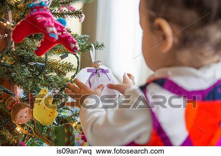 Little girl looking at angel ornament on Christmas tree View Large Photo Image Stock Photography - Little girl looking at angel ornament on Christmas tree. Fotosearch