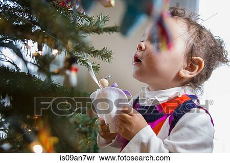Little girl looking at angel ornament on Christmas tree View Large Photo Image Stock Photography - Little girl looking at angel ornament on Christmas tree. Fotosearch