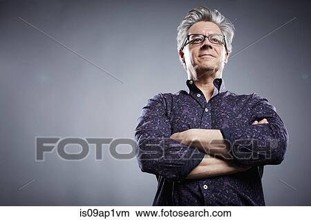 Picture - Low angle studio portrait of mature businessman with arms folded. Fotosearch