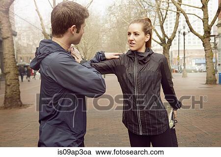 Stock Image - "Male and female runners warming up on misty tree lined street, Pioneer Square, Seattle, USA". Fotosearch