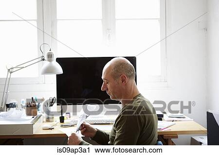 Stock Image - Mature man making paper airplane in creative studio. Fotosearch
