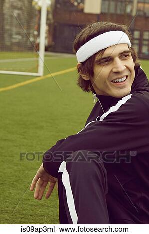 Stock Image - Mid adult man warming up on soccer pitch. Fotosearch