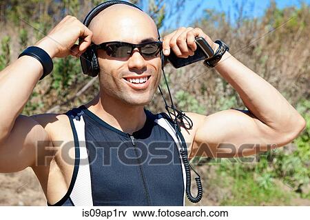 "Mid adult man wearing headphones and holding MP3 player, outdoors" View Large Photo Image Stock Photo - "Mid adult man wearing headphones and holding MP3 player, outdoors". Fotosearch