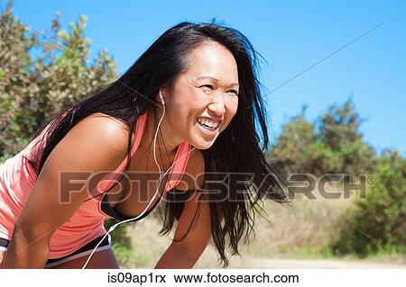 "Mid adult woman in sports clothing, wearing earphones, looking straight ahead" View Large Photo Image Stock Photo - "Mid adult woman in sports clothing, wearing earphones, looking straight ahead". Fotosearch