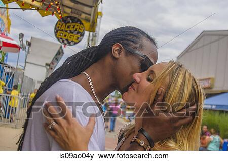 Multi ethnic mature couple kissing at amusement park View Large Photo Image Stock Photo - Multi ethnic mature couple kissing at amusement park. Fotosearch