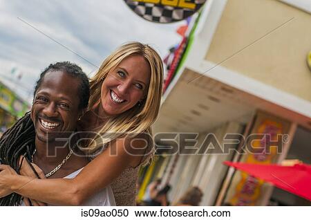 Multi ethnic mature couple sharing piggyback at amusement park View Large Photo Image Stock Image - Multi ethnic mature couple sharing piggyback at amusement park. Fotosearch