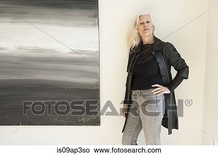 Portrait of a confident senior woman by painting on wall View Large Photo Image Picture - Portrait of a confident senior woman by painting on wall. Fotosearch
