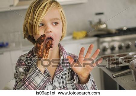 Stock Photograph - Portrait of boy licking chocolate cake mixture from fingers. Fotosearch