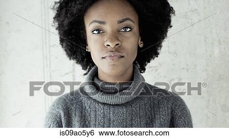 Stock Photograph - Portrait of confident young woman in front of wall. Fotosearch