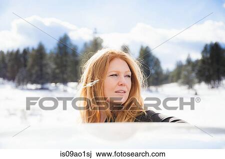 Portrait of mid adult woman gazing over car roof in snow covered landscape View Large Photo Image Stock Image - Portrait of mid adult woman gazing over car roof in snow covered landscape. Fotosearch