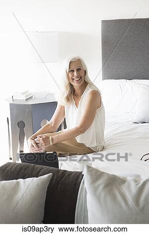"Portrait of senior woman sitting on bed, smiling" View Large Photo Image Stock Photo - "Portrait of senior woman sitting on bed, smiling". Fotosearch