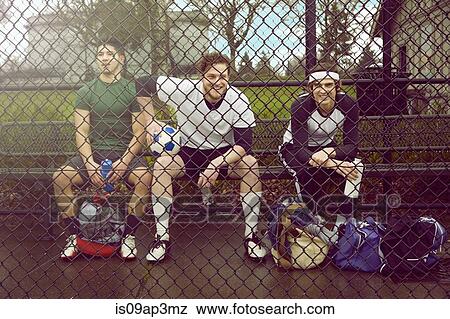 Portrait of three male soccer players sitting behind wire fence View Large Photo Image Stock Photo - Portrait of three male soccer players sitting behind wire fence. Fotosearch