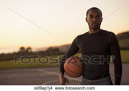 "Portrait of young man holding basketball, outdoors" View Large Photo Image Picture - "Portrait of young man holding basketball, outdoors". Fotosearch