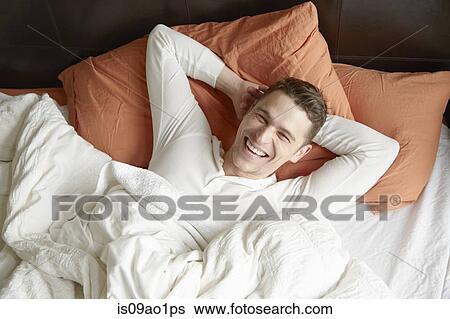 Portrait of young man lying in bed laughing View Large Photo Image Stock Photograph - Portrait of young man lying in bed laughing. Fotosearch