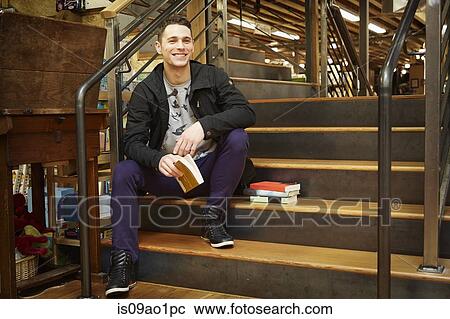 Stock Image - Portrait of young man sitting on book store stairway. Fotosearch