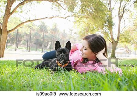 Portrait of young woman and dog lying in park together View Large Photo Image Stock Photo - Portrait of young woman and dog lying in park together. Fotosearch