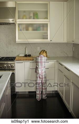 Stock Image - Rear view of boy sulking at kitchen counter. Fotosearch