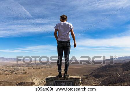 Stock Photograph - "Rear view of young man looking out over landscape, Anza-Borrego Desert State Park, California, USA". Fotosearch