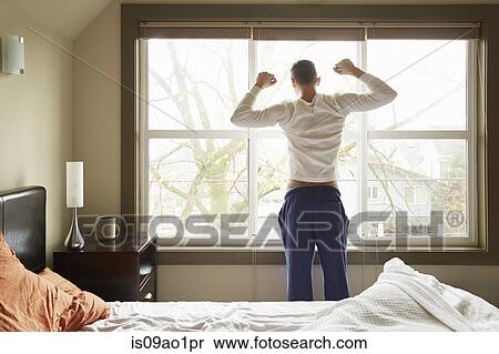 Rear view of young man stretching in front of bedroom window View Large Photo Image Stock Photography - Rear view of young man stretching in front of bedroom window. Fotosearch