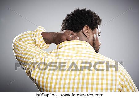 Stock Image - Rear view studio portrait of mid adult businessman massaging neck. Fotosearch