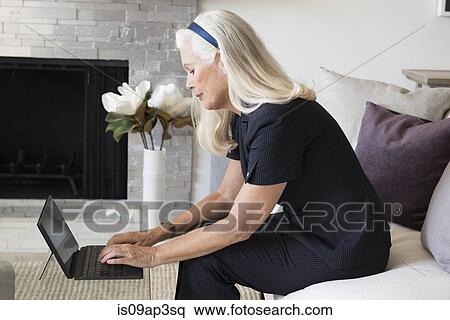 Senior female businesswoman using laptop in living room View Large Photo Image Stock Photography - Senior female businesswoman using laptop in living room. Fotosearch