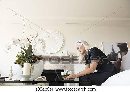 Senior female businesswoman using laptop in living room View Large Photo Image Stock Photography - Senior female businesswoman using laptop in living room. Fotosearch