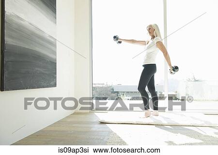 Stock Image - Senior woman exercising with dumbbells. Fotosearch
