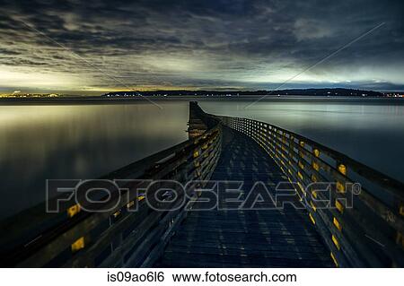 Stock Photograph - "Silhouetted view of winding wooden pier over Puget Sound at dawn, Seattle, Washington State, USA". Fotosearch