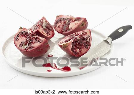Stock Image - Still life of quartered pomegranate on plate. Fotosearch