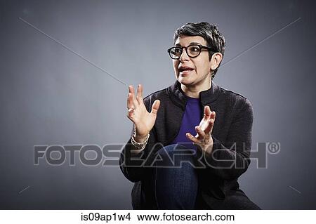 Picture - Studio portrait of mature businesswoman explaining with open hands. Fotosearch
