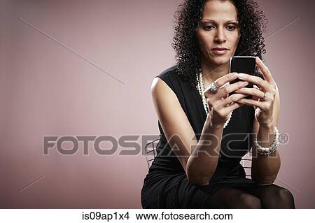 Studio portrait of mature businesswoman reading smartphone messages View Large Photo Image Picture - Studio portrait of mature businesswoman reading smartphone messages. Fotosearch