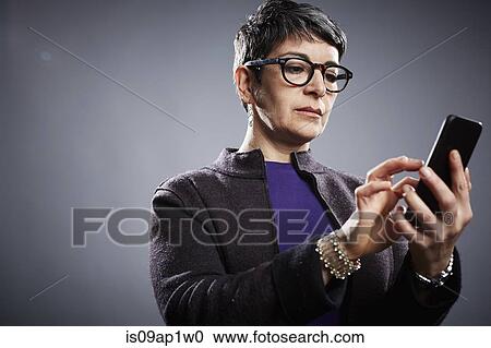 Studio portrait of mature businesswoman texting on smartphone View Large Photo Image Stock Image - Studio portrait of mature businesswoman texting on smartphone. Fotosearch