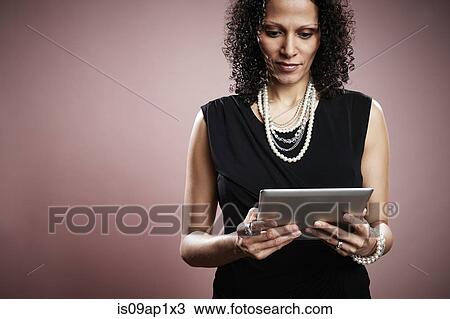 Studio portrait of mature businesswoman looking at digital tablet View Large Photo Image Stock Image - Studio portrait of mature businesswoman looking at digital tablet. Fotosearch