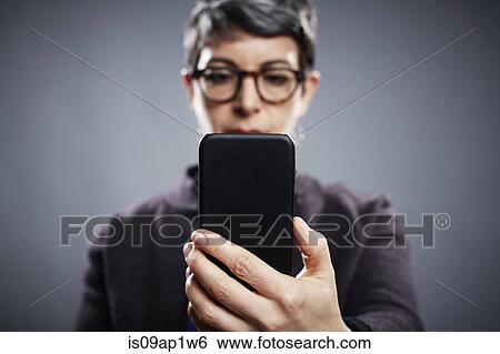 Stock Photograph - Studio portrait of mature businesswoman reading smartphone. Fotosearch