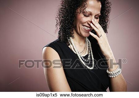 Stock Photography - Studio portrait of mature woman with hand on face giggling. Fotosearch
