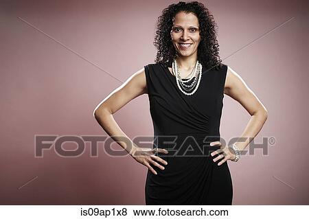 Stock Photo - Studio portrait of smiling mature businesswoman with hands on hips. Fotosearch