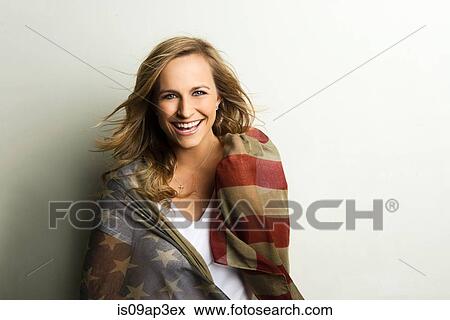 Stock Photo - Studio portrait of smiling young woman wrapped in American flag. Fotosearch