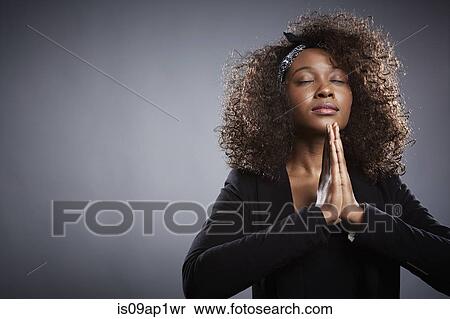 Stock Photography - Studio portrait of young businesswoman praying. Fotosearch