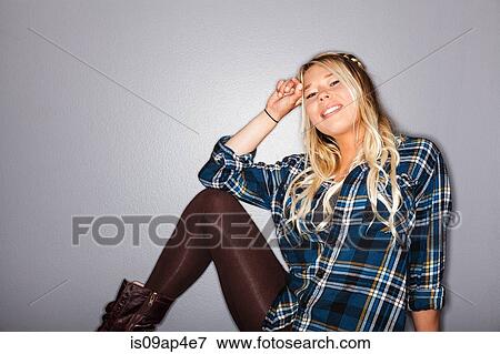 Stock Photo - Studio portrait of young woman sitting on floor posing. Fotosearch