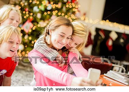 Teenage girl and brothers taking selfie on smartphone at christmas View Large Photo Image Stock Image - Teenage girl and brothers taking selfie on smartphone at christmas. Fotosearch