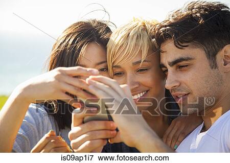 "Three friends looking at smartphone, outdoors" View Large Photo Image Stock Photo - "Three friends looking at smartphone, outdoors". Fotosearch