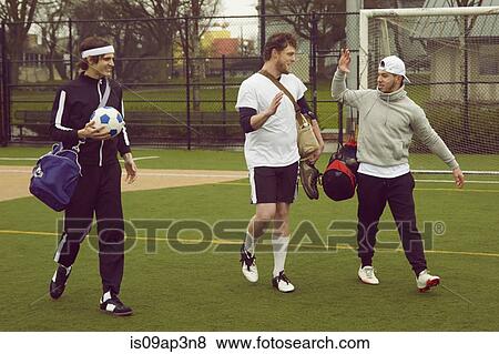 Three male soccer players walking and talking on soccer pitch View Large Photo Image Stock Photo - Three male soccer players walking and talking on soccer pitch. Fotosearch