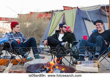 Picture - "Three young male friends sitting chatting around campfire, Anza-Borrego Desert State Park, California, USA". Fotosearch