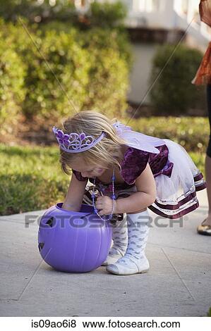 Stock Photo - Toddler reaching into Jack O' Lantern bucket. Fotosearch